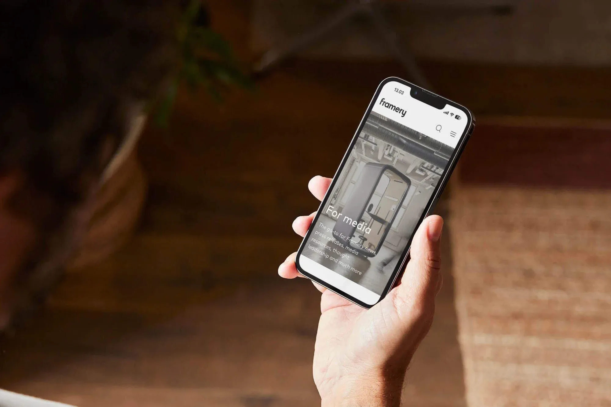 Hand holding a phone with a Framery product page.