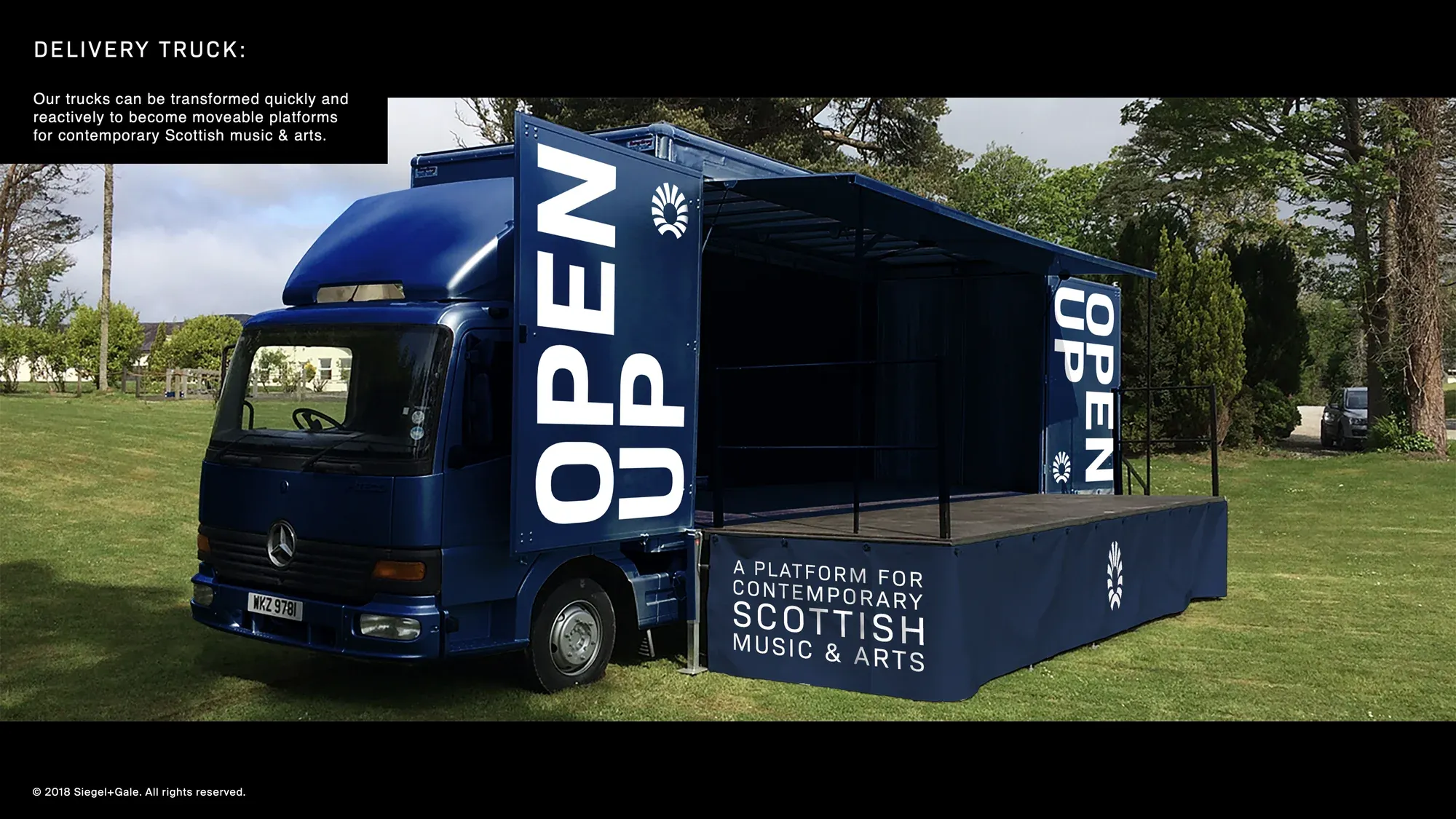 A blue Chivas Brothers truck with OPEN UP on its side, opened up as a stage.
