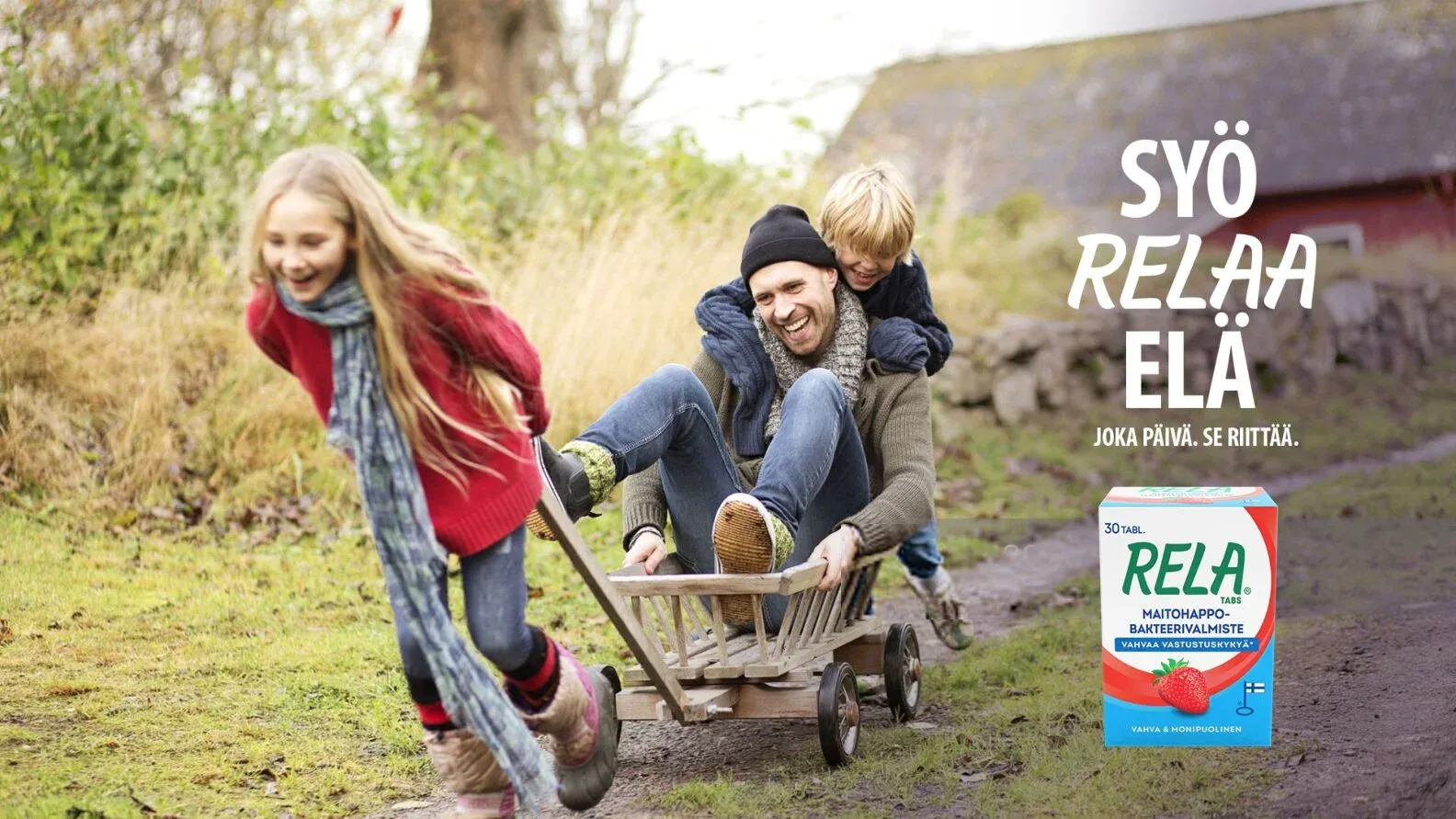 A father pushing two laughing children in a wooden cart, beside the line Syö. RELAA. Elä. and a RELA pack.